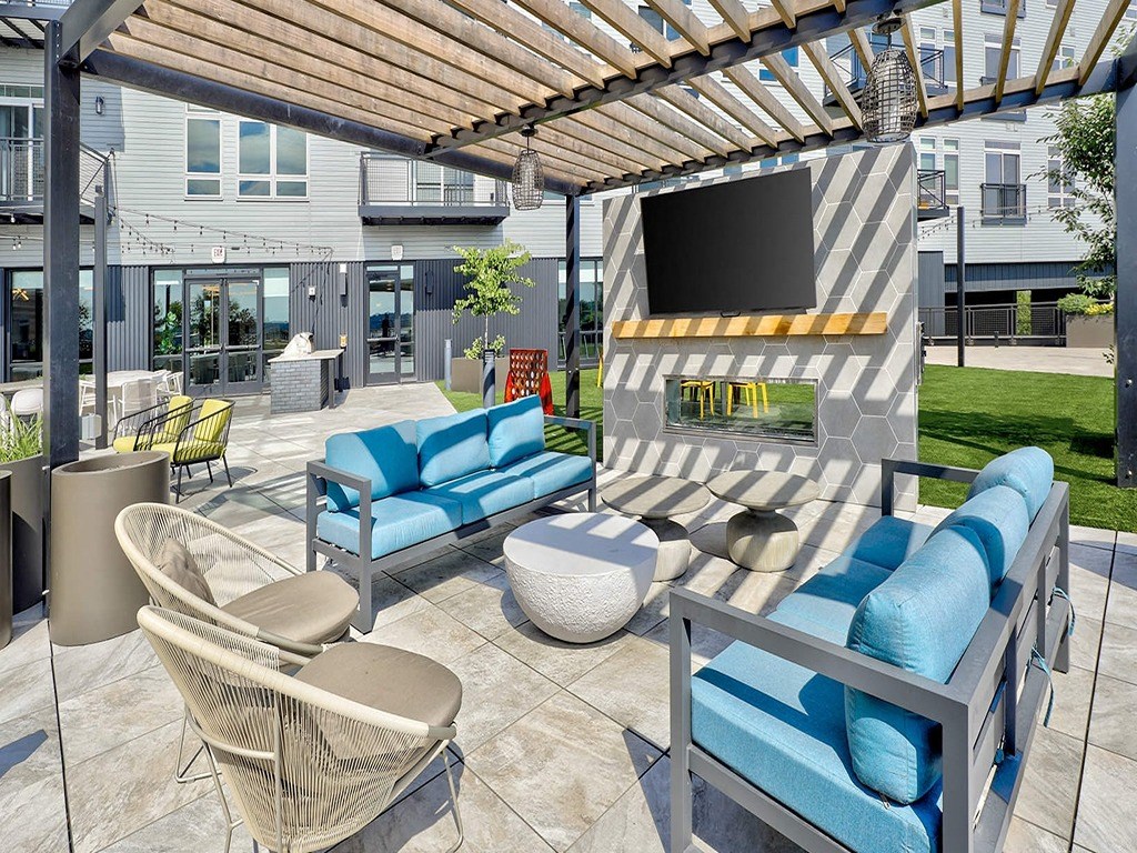 a patio with blue couches and chairs and a television